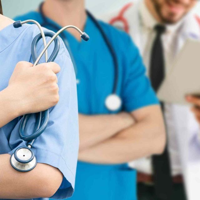 Médicos y enfermeras con uniformes médicos y estetoscopios trabajando en un entorno médico.