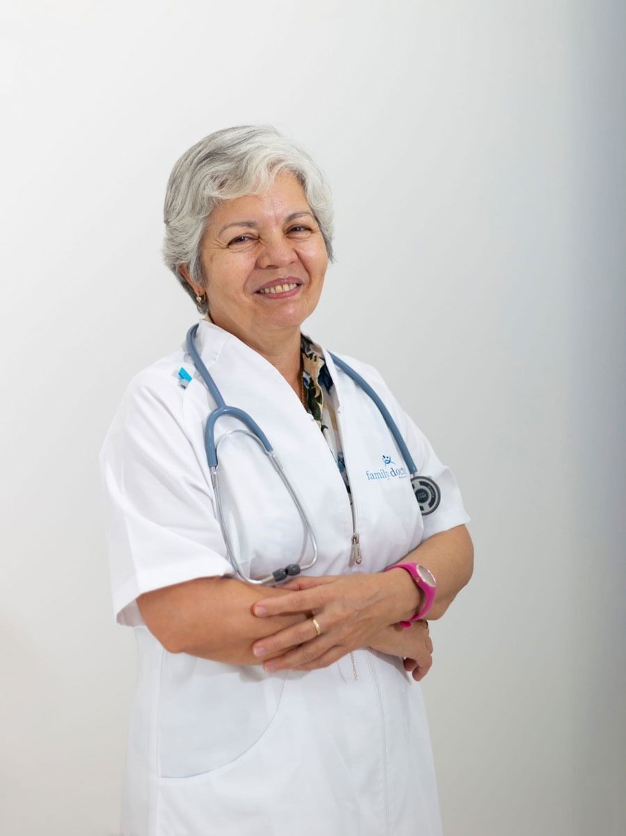 Mujer de cabello gris, con bata blanca y estetoscopio, sonriendo.