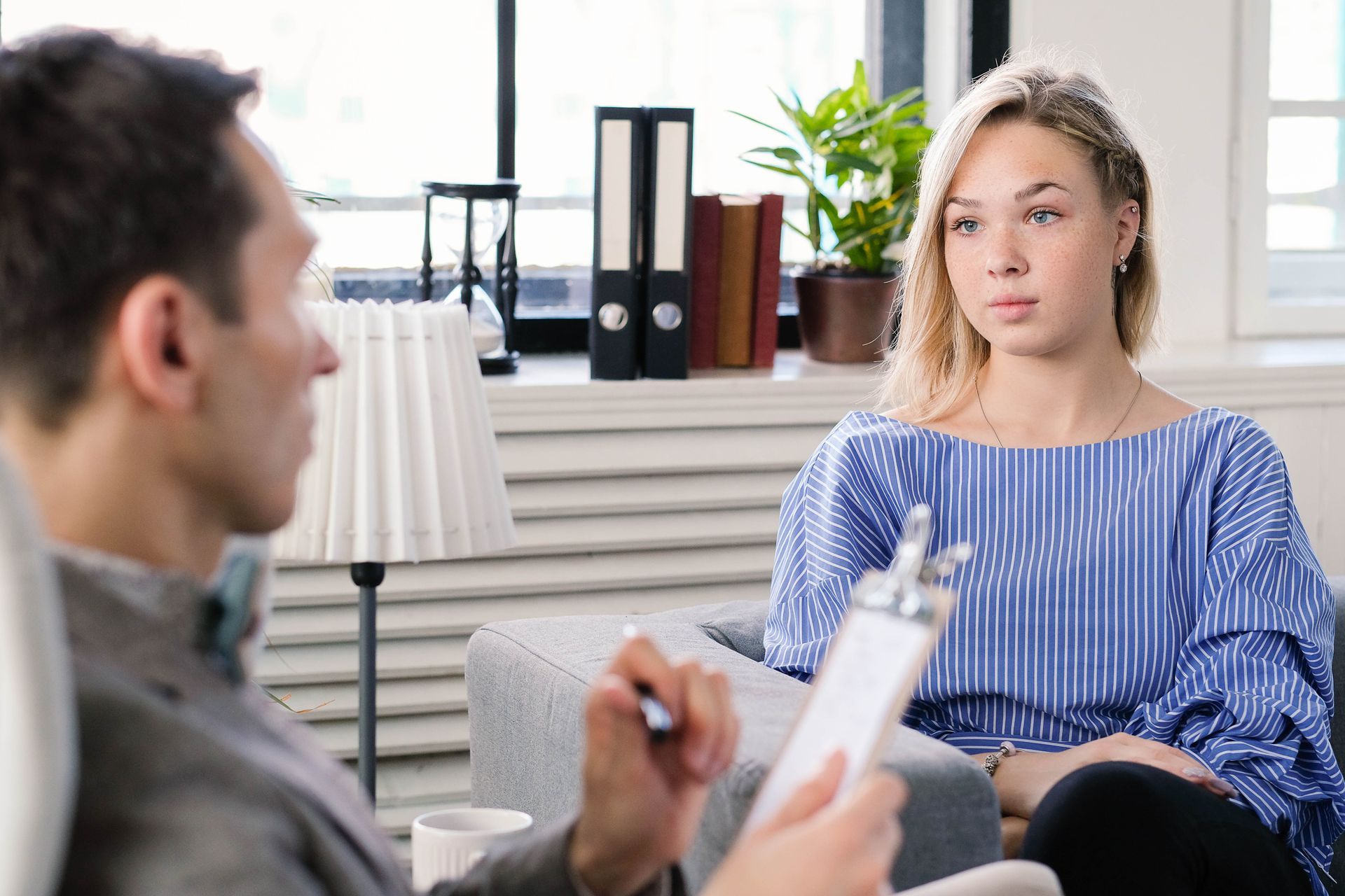 Terapeuta y cliente en sesión; mujer con camisa azul parece preocupada.