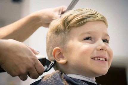 Mitarbeiter von Coiffure mina schneidet Kind die Haare