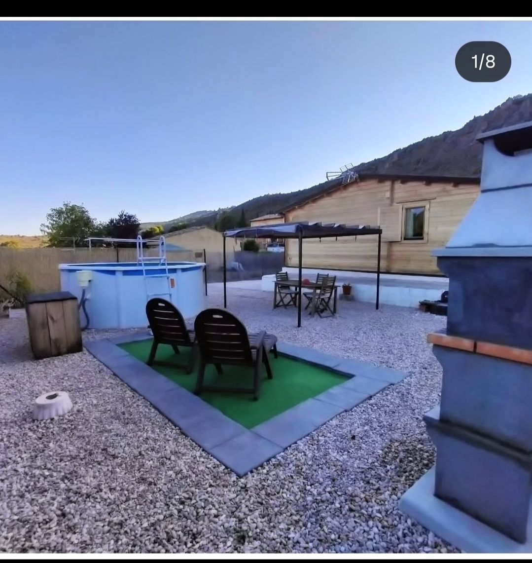 Patio trasero con piscina, zona de estar y vista a la montaña, en un día soleado.