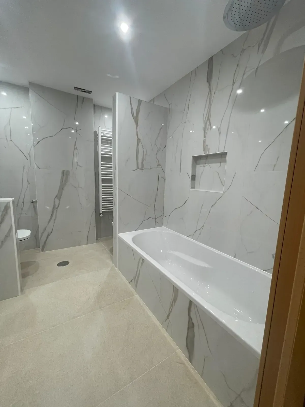 Baño moderno con azulejos blancos, bañera, ducha a ras de suelo y suelo de baldosas beige