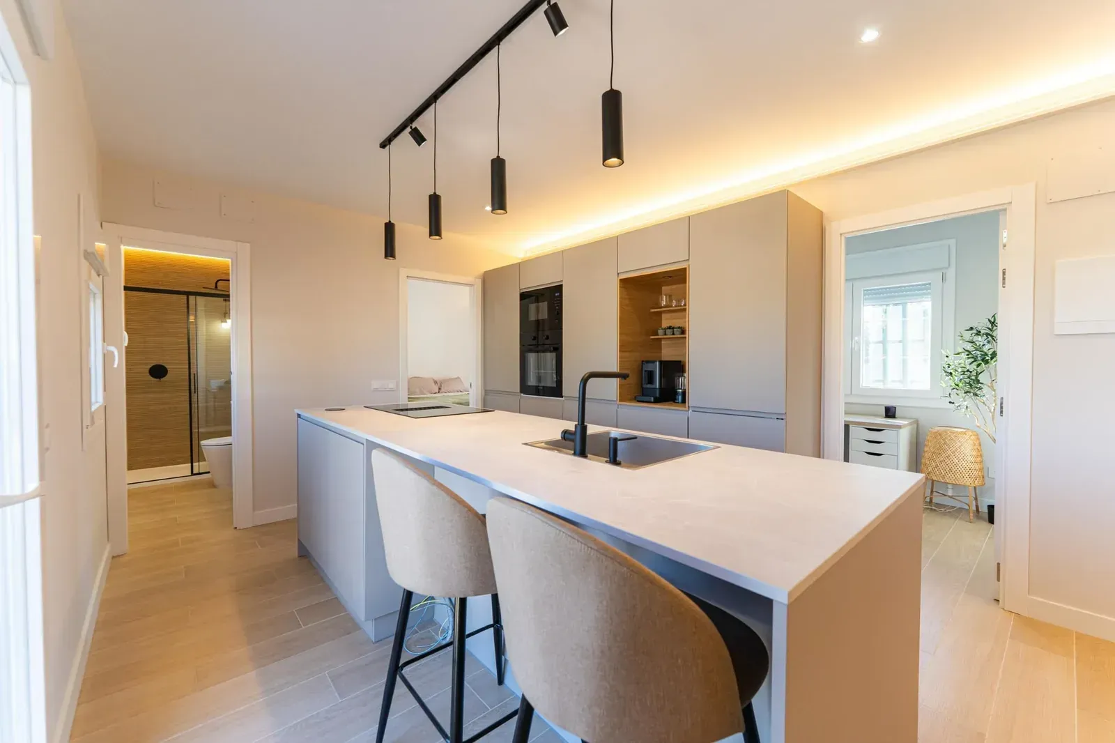 Cocina moderna con una isla grande, taburetes, lámparas colgantes y cálidos suelos de madera