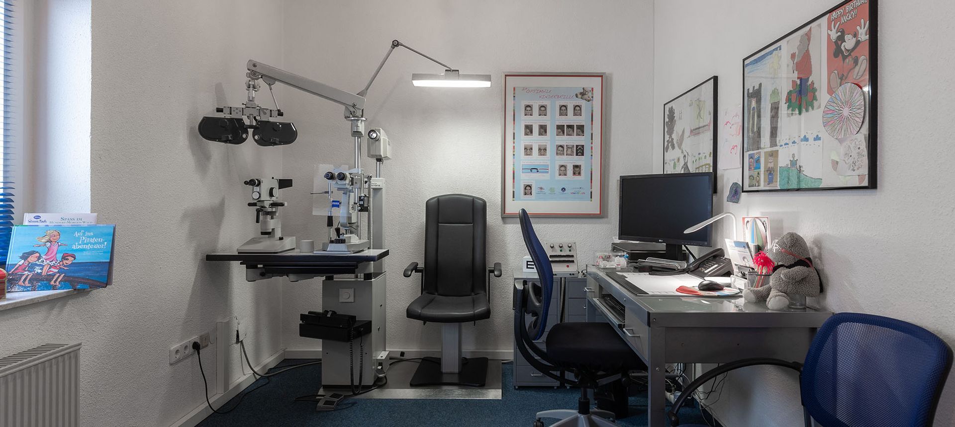 Eine Augenarztpraxis mit Stuhl, Schreibtisch und Computer.
