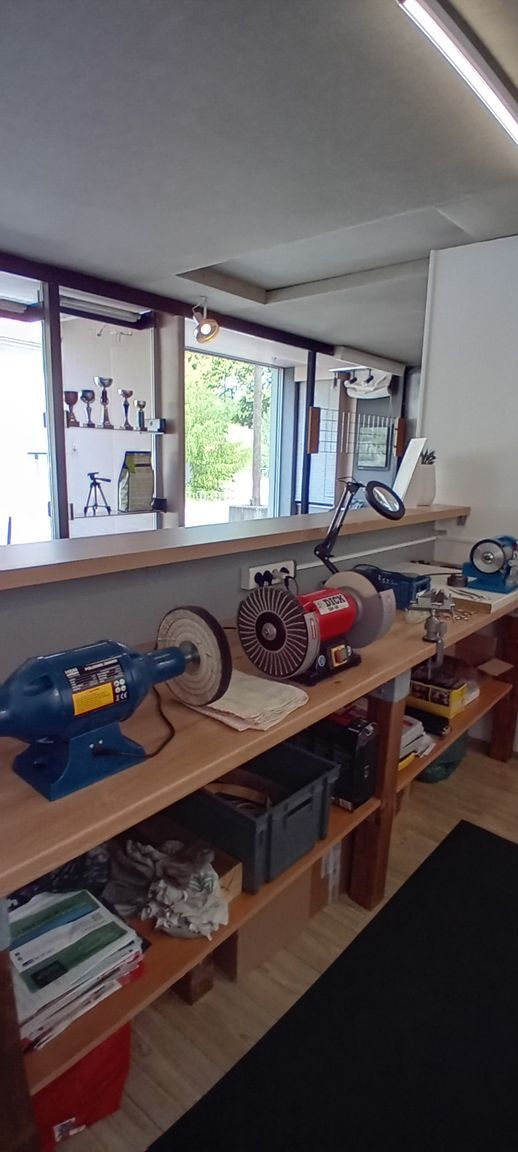 Établi avec outils  et petites machines d'affûtage dans un atelier près d'une fenêtre lumineuse.