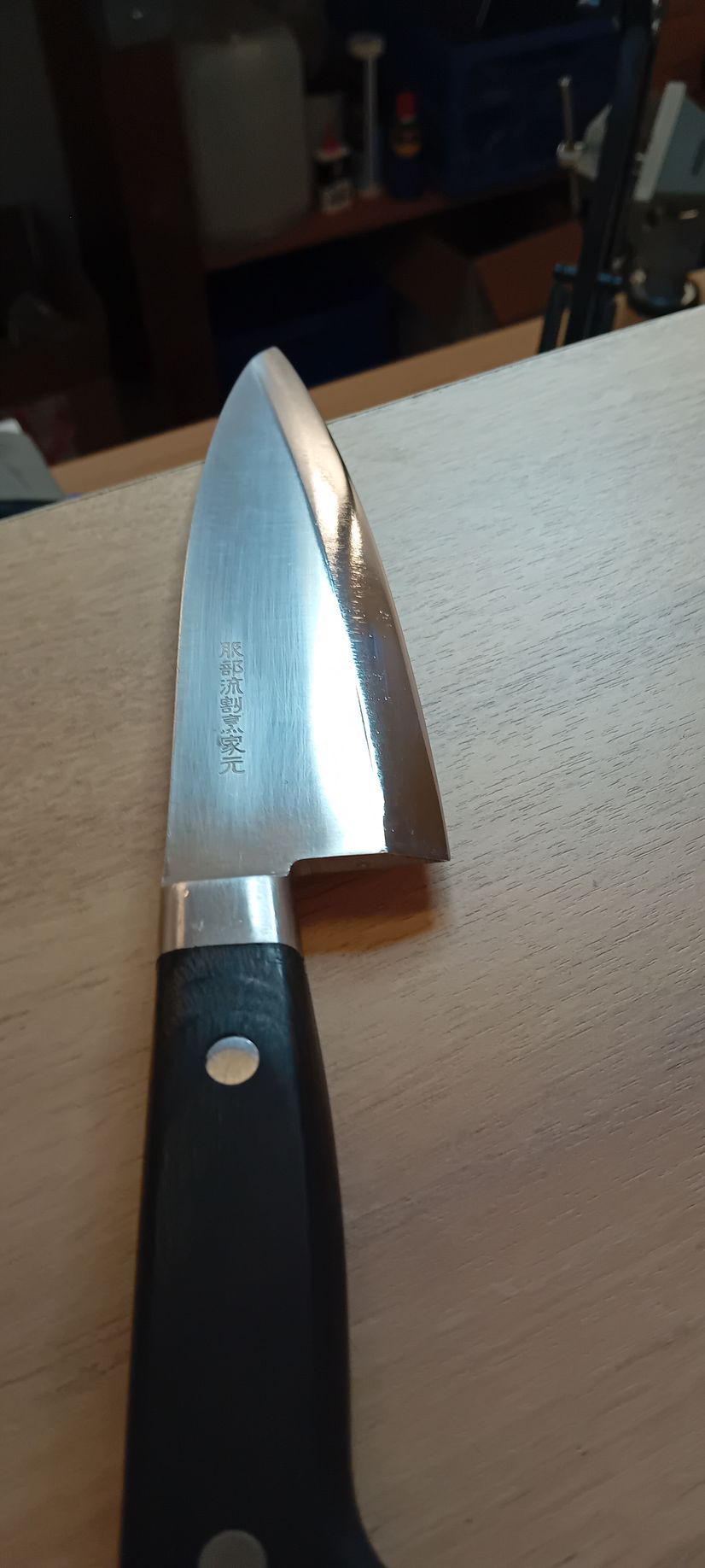 Couteau de cuisine à manche noir posé sur un plan de travail, lame acier.