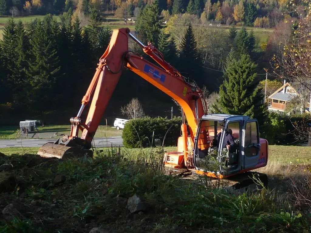 Tractopelle qui aplanit un terrain en pente