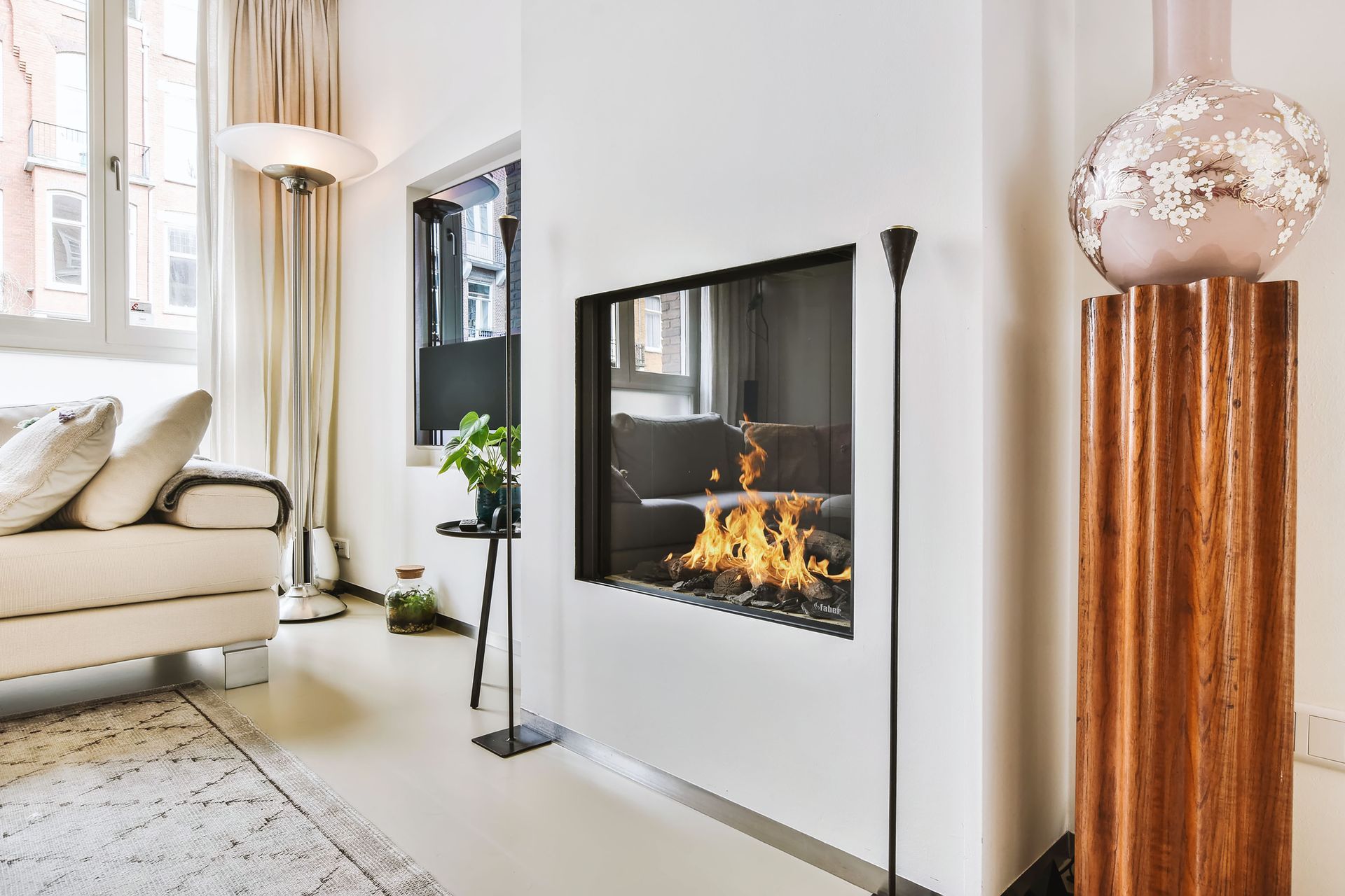 Salon moderne avec cheminée murale, canapé crème et lampe sur pied en cuivre