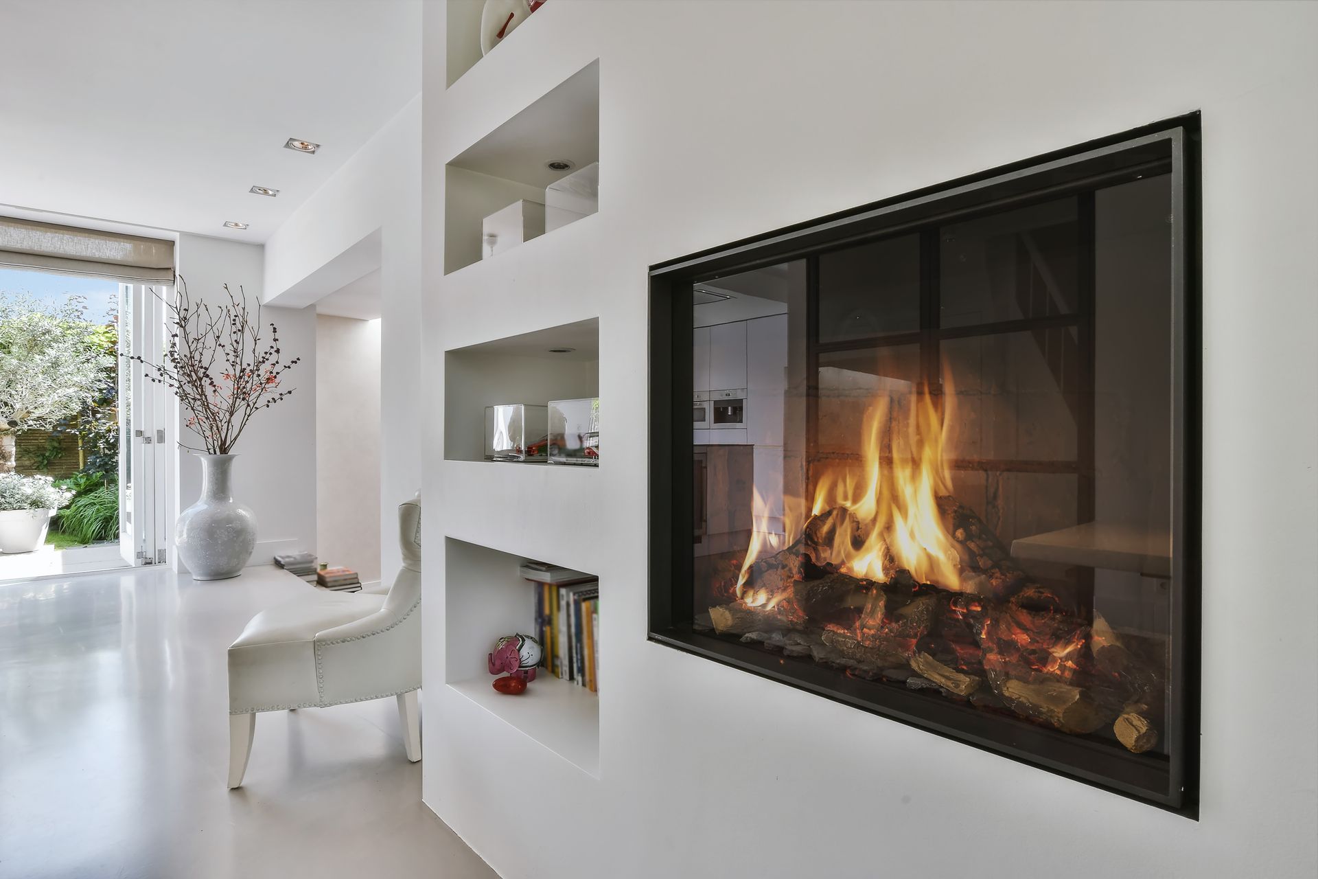 Salon blanc avec cheminée murale, étagères intégrées et lumière naturelle