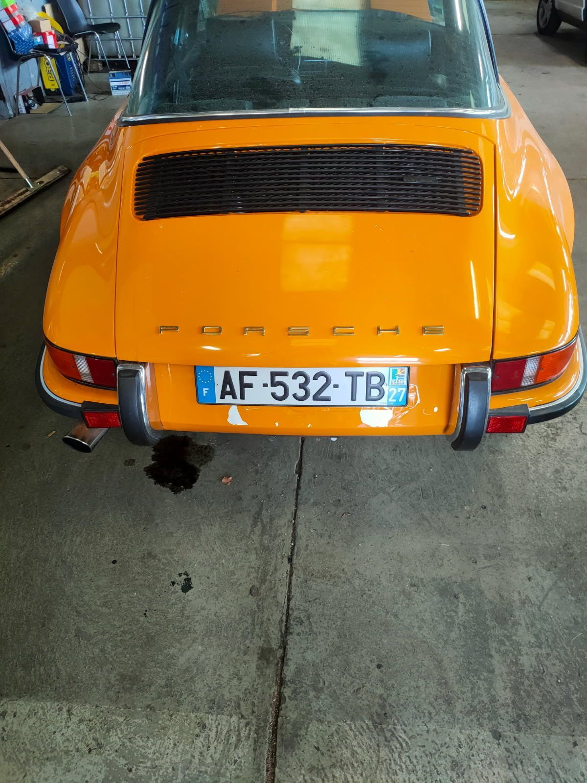 Une Porsche Targa orange est garée devant une maison