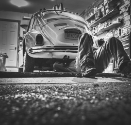 Un homme est allongé sur le sol sous une voiture dans un garage.