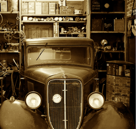 Une photo en noir et blanc d'une vieille voiture dans un garage