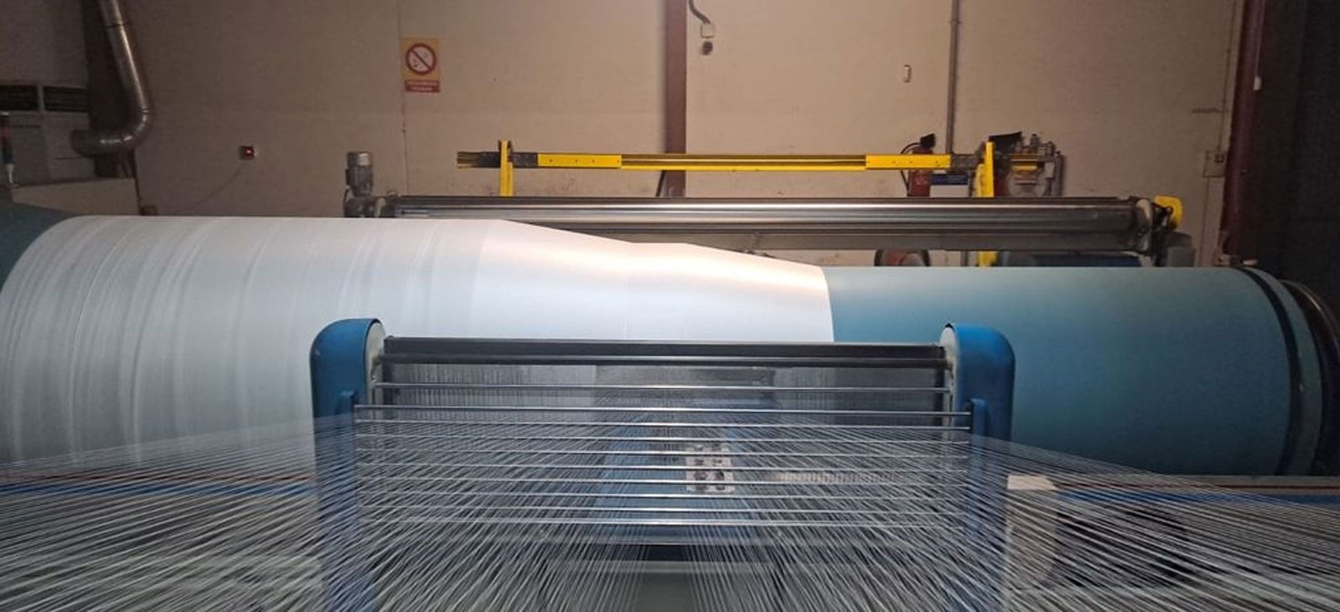 Una máquina está cortando un trozo de plástico en una fábrica.