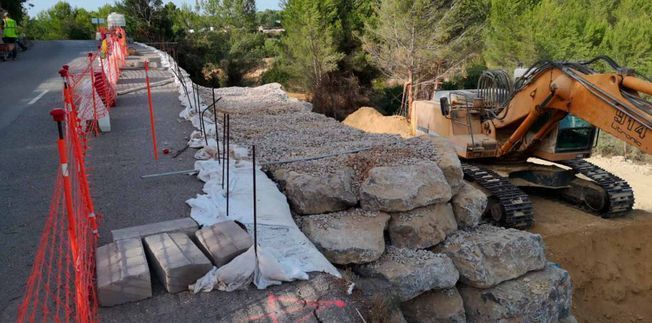 Montón de arena delante de un muro de piedra, sitio de construcción.