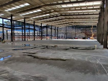 Gran interior de almacén de hormigón con vigas metálicas y suelo sin terminar.