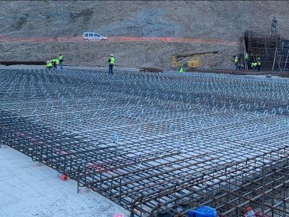 Trabajadores instalando una rejilla de varillas de refuerzo en un sitio de construcción; luz del día.