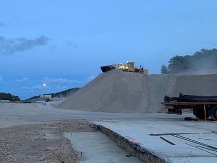 Bulldozer sobre un montón de arena en un sitio de construcción al anochecer.