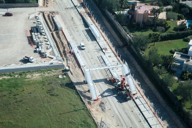 Vista aérea de la construcción de una carretera; una grúa levanta una sección de hormigón.