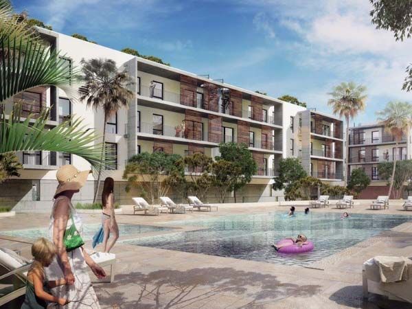 Complejo de apartamentos con piscina. La gente se relaja y nada. Palmeras, un entorno soleado.