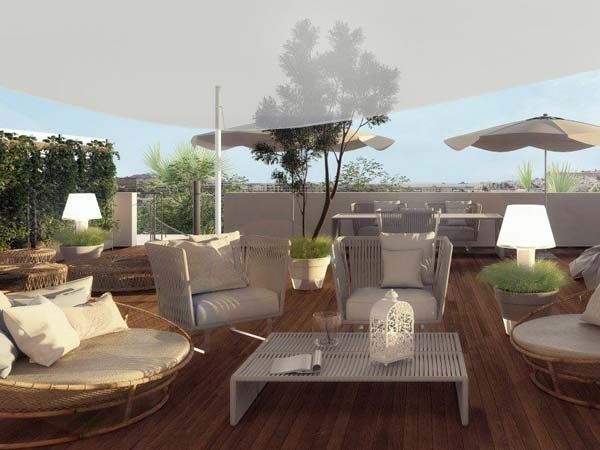 Patio en la azotea con tumbonas, comedor y sombrillas. Terraza de madera, colores neutros y vegetación.