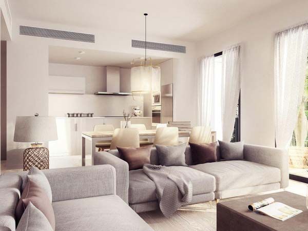 Moderna sala de estar y cocina con sofás grises, paredes blancas y comedor abierto.