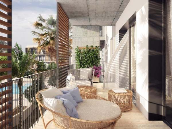 Balcón con muebles de mimbre, palmeras y vista a la piscina.