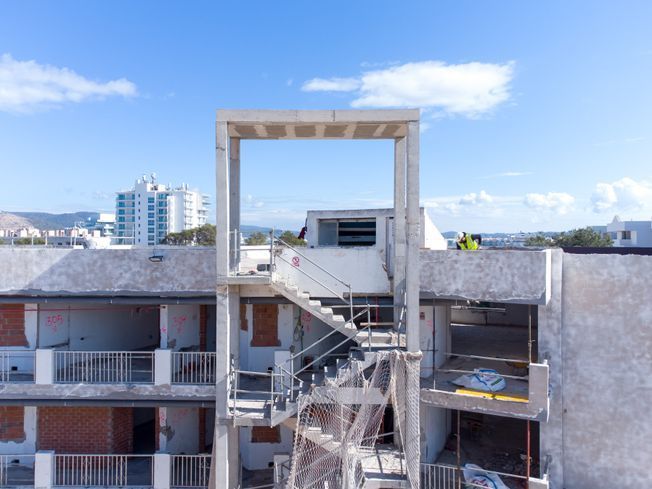 Construcción de escalera de hormigón en edificio, con estructura abierta y cielo raso.
