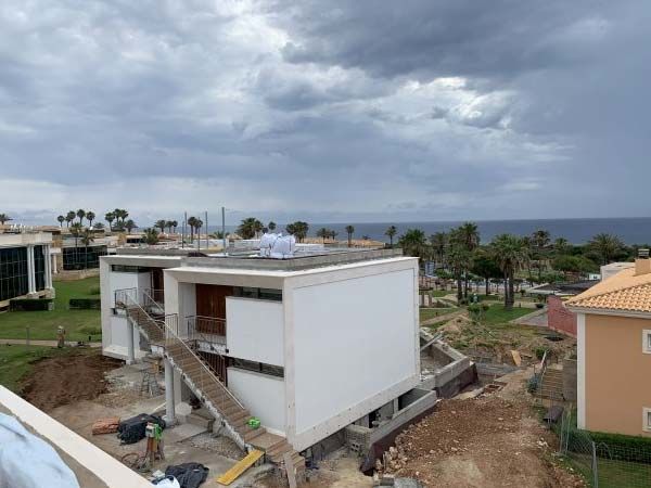 Edificio beige y blanco de dos plantas con escaleras exteriores y puertas iluminadas al anochecer.