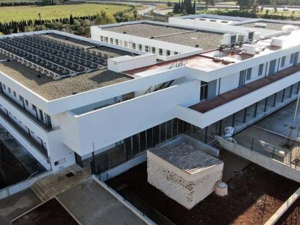Edificio moderno blanco con paneles solares en el techo; vista exterior con luz natural.