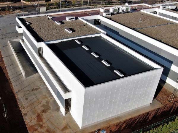 Edificio moderno de color blanco con techo plano de color negro; toma exterior.