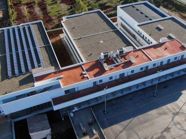 Vista aérea de un edificio blanco con tejas rojas y paneles solares.
