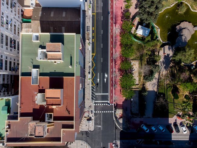 Vista aérea de una calle de la ciudad con edificios a ambos lados y una vía central con carriles para bicicletas.
