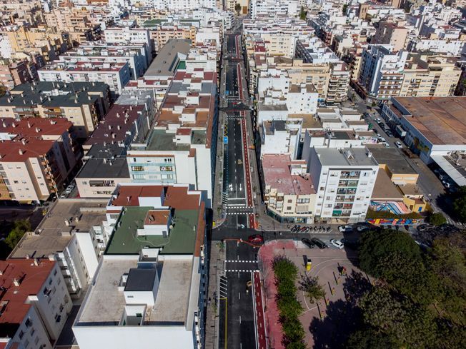 Vista aérea de una calle de la ciudad con edificios a ambos lados y una vía central con carriles para bicicletas.