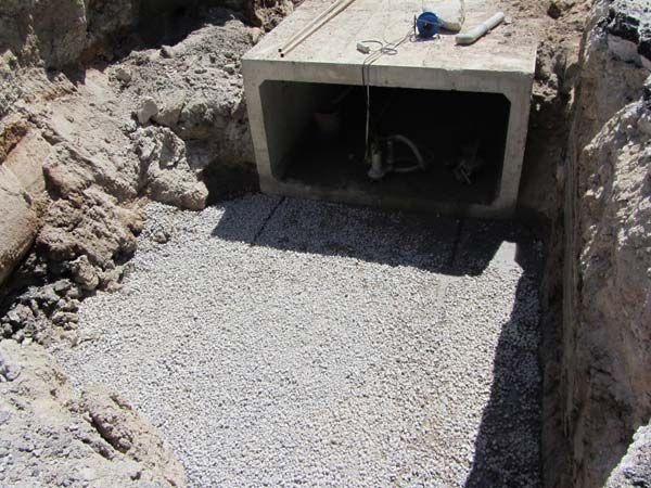Alcantarilla de cajón de hormigón colocada en lecho de grava, sitio excavado.
