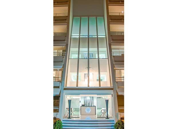 Recepción con escritorio blanco y logotipo iluminado en azul. Suelo de mármol.