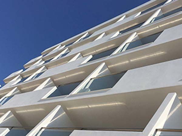 Edificio moderno blanco con balcones contra un cielo azul.