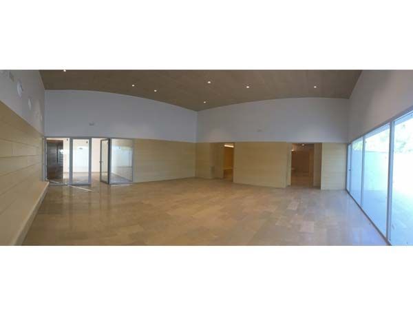 Interior espacioso y vacío con paredes claras, techo alto y ventanas grandes; posiblemente un espacio comercial.