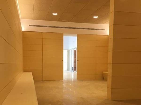 Interior con puertas y paredes de madera clara; luz solar a través de la puerta, color beige.