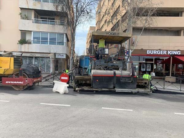 Resurfacing en curso. Obreros y maquinaria de construcción en la calle frente a un Burger King.
