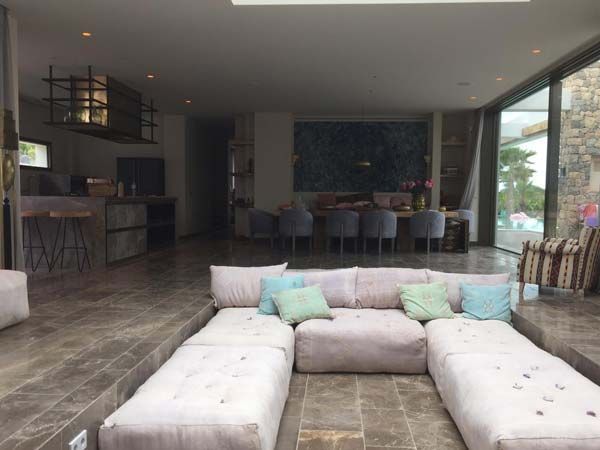 Piscina con pilar de piedra junto a un edificio moderno bajo un cielo nublado.