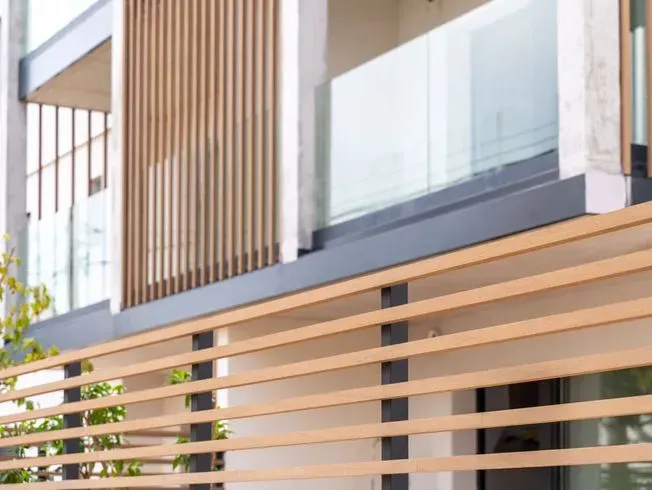 Edificio moderno con balcones de listones de madera y barandillas de cristal.