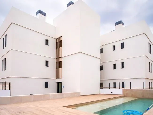 Edificio de apartamentos blanco con piscina.
