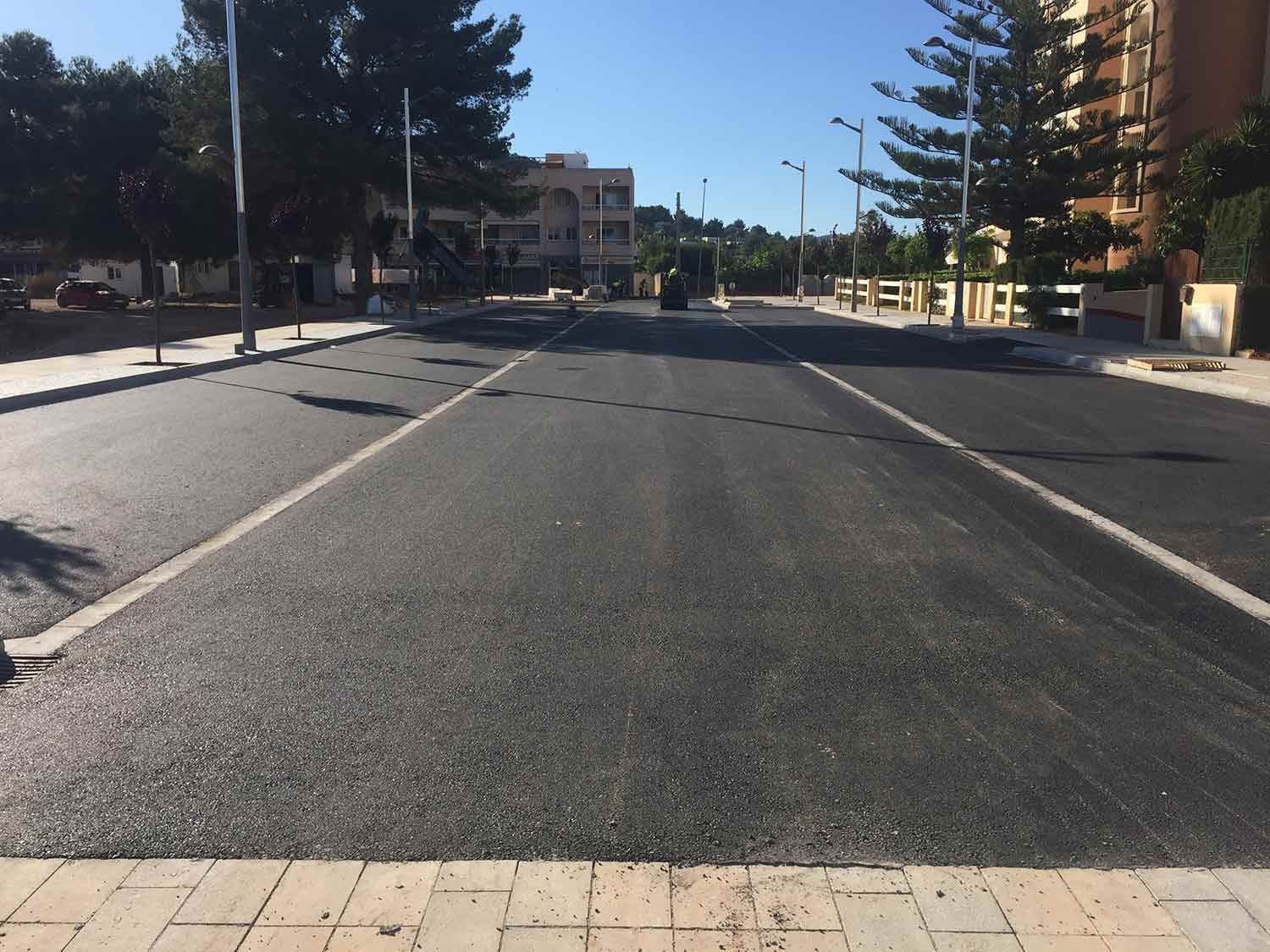 Carretera asfaltada recién pavimentada con marcas blancas en los carriles; día soleado.