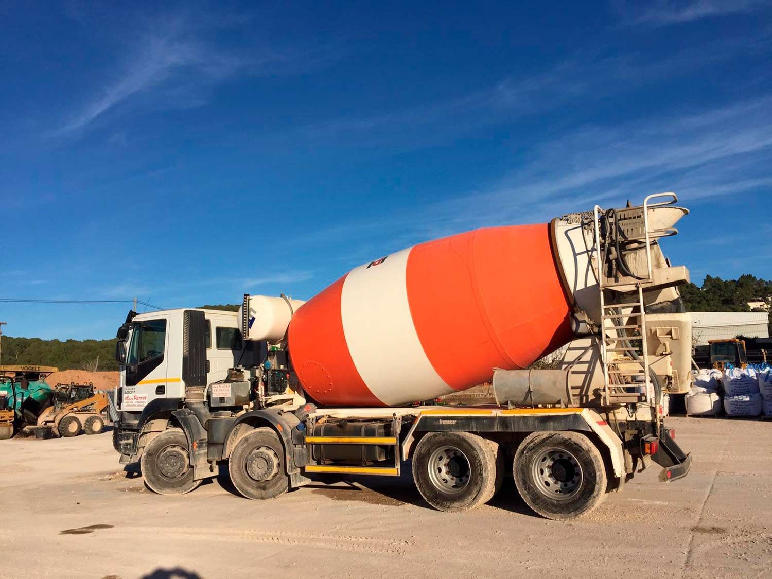 Camión de cemento con bidón naranja y blanco en un día soleado.