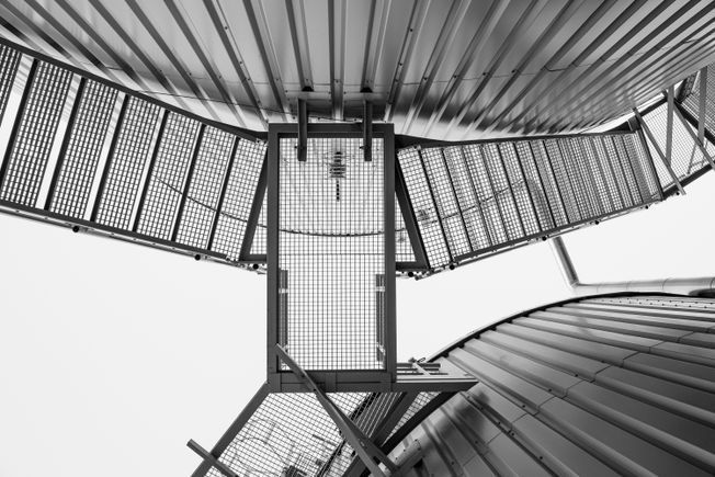Fotografía en blanco y negro que mira hacia arriba hacia pasarelas y estructuras de metal.