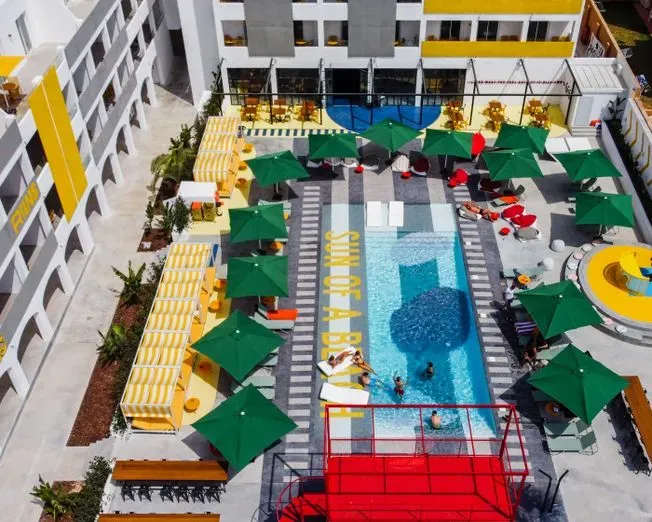 Vista aérea: piscina con sombrillas verdes, sillas para descansar y la frase