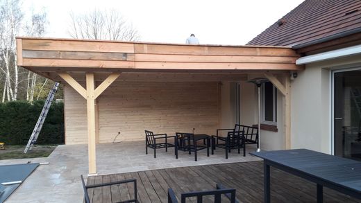 Patio couvert avec poutres en bois, table et chaises de jardin à côté d'une maison.