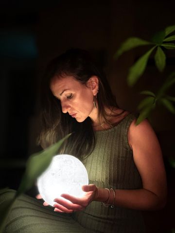 Una mujer está sentada en una silla con las piernas cruzadas y sonriendo.
