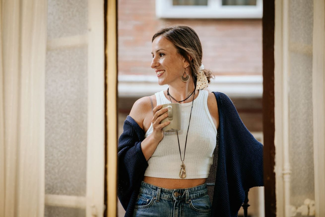 Una mujer está sentada en una silla con las piernas cruzadas y sonriendo.