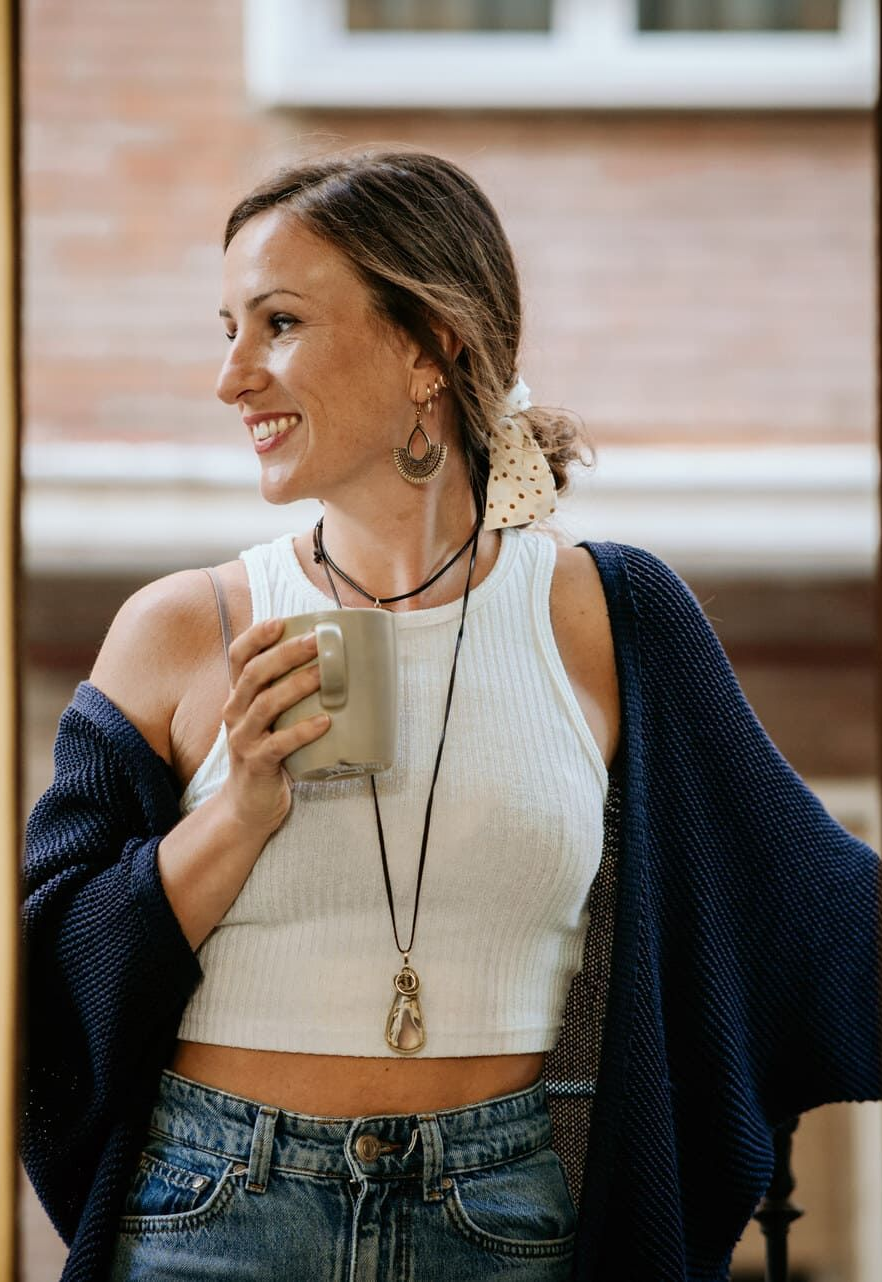 Una mujer está sentada en una silla con las piernas cruzadas y sonriendo.